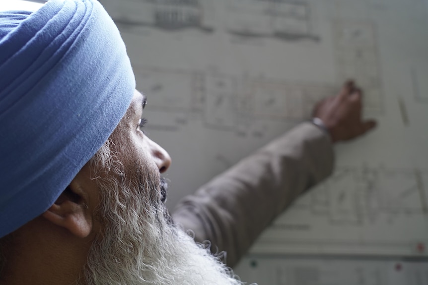 A Sikh pointing at a chart