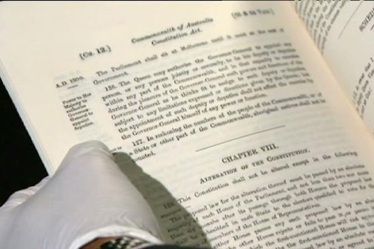 Gloved hands hold open pages of Australian Constitution