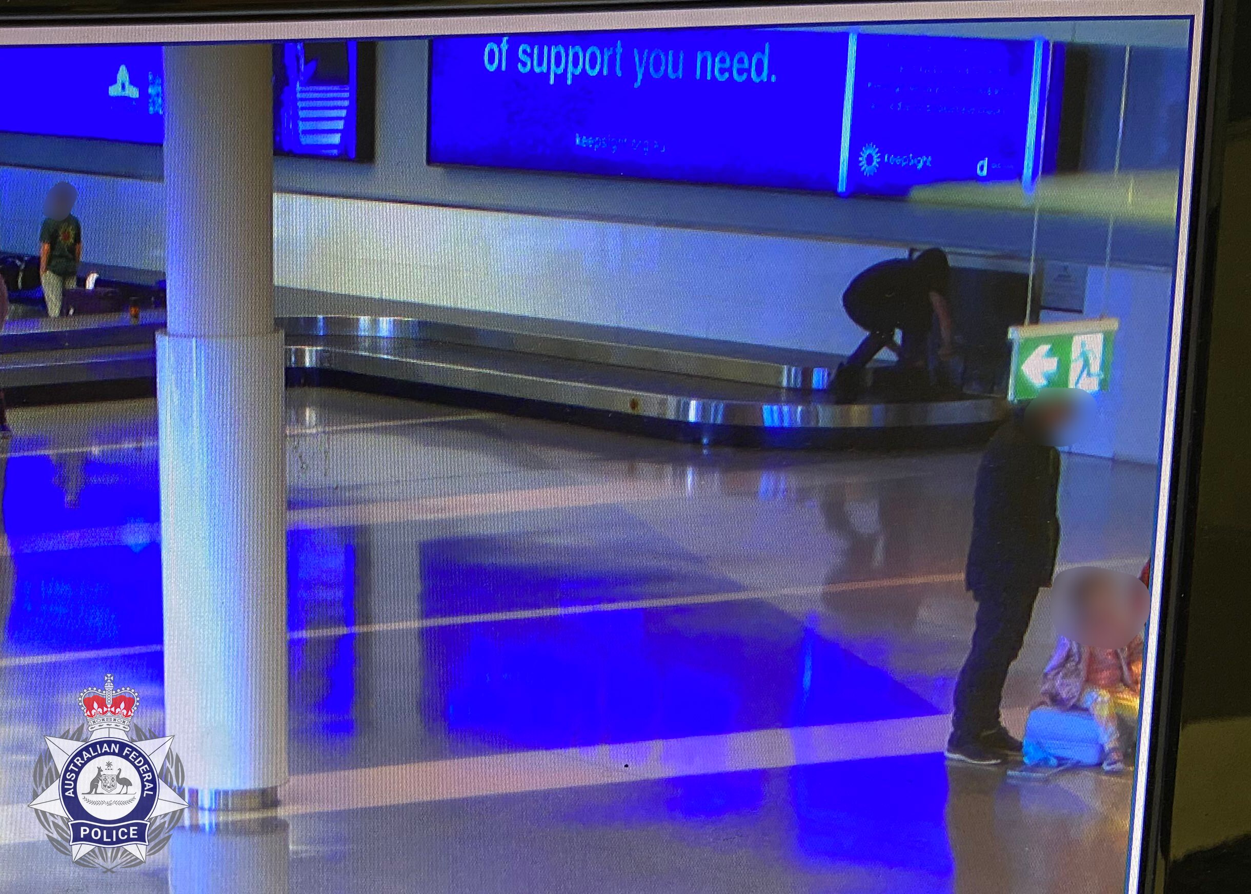 CCTV image of a young person in dark clothing on an airport baggage carousel.