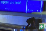 CCTV image of a young person in dark clothing on an airport baggage carousel.