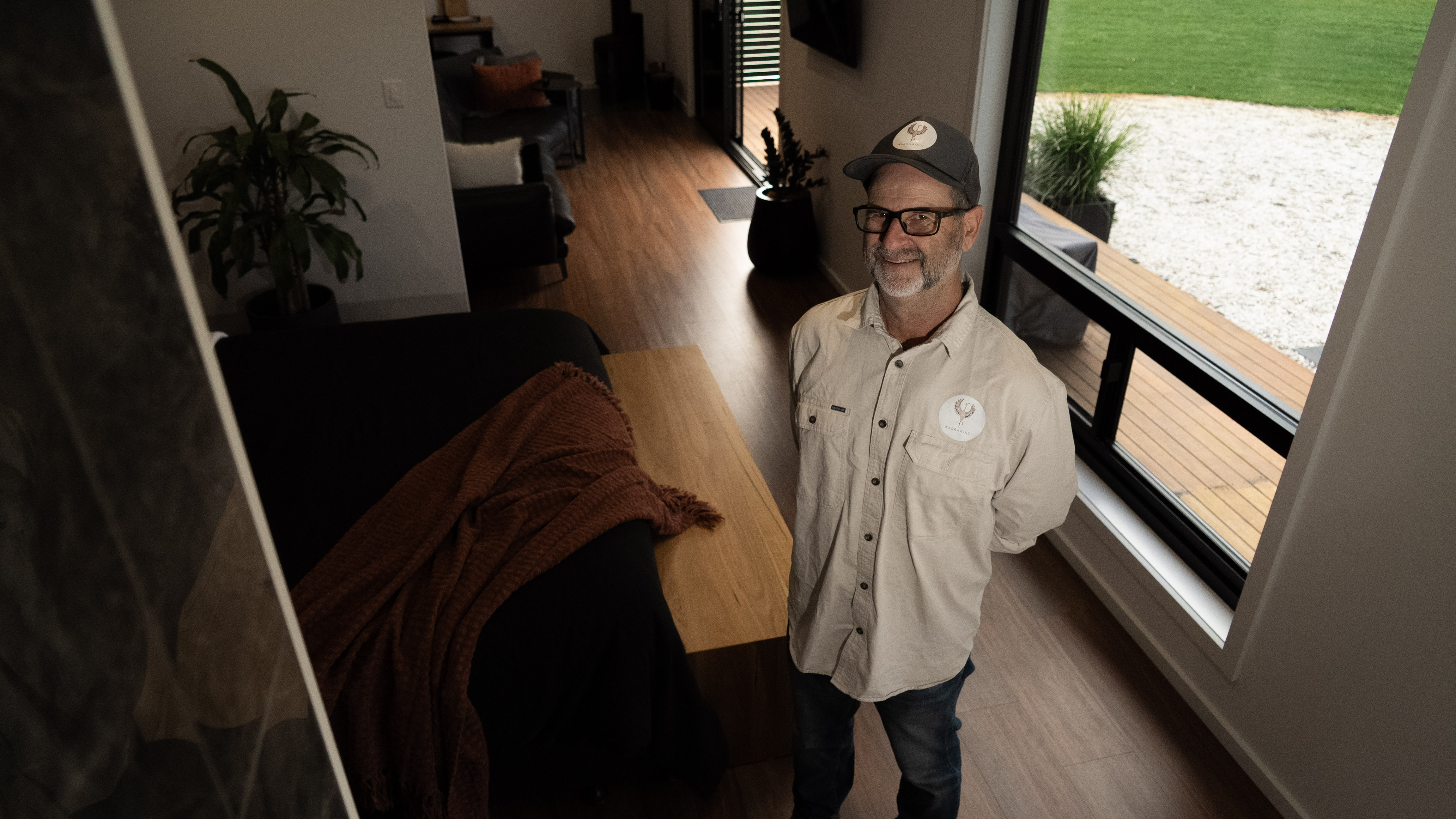A man stands in a modern living space with wooden floor