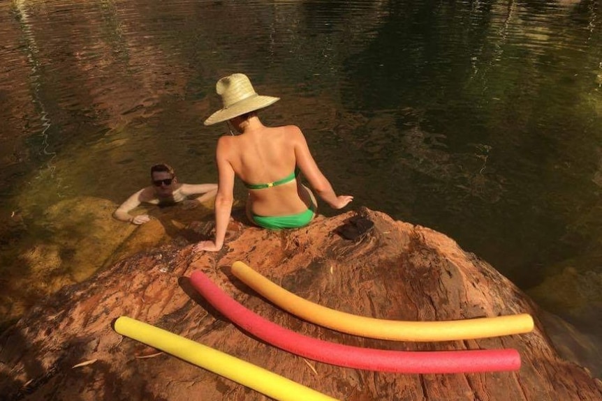 Two people swimming in a water hole in Karijini National Park