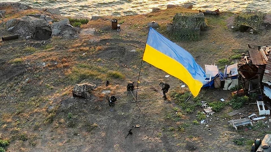 Ukrainian soldiers install a large state flag on Snake island.