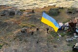 Ukrainian soldiers install a large state flag on Snake island.