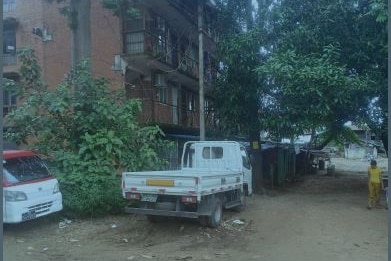 A brick apartment building in Myanmar with a ute outside. 