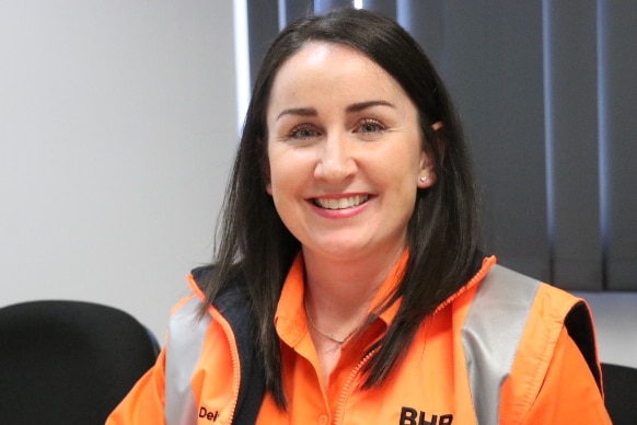 Close-up of women sitting at desk, wearing hi-vis.