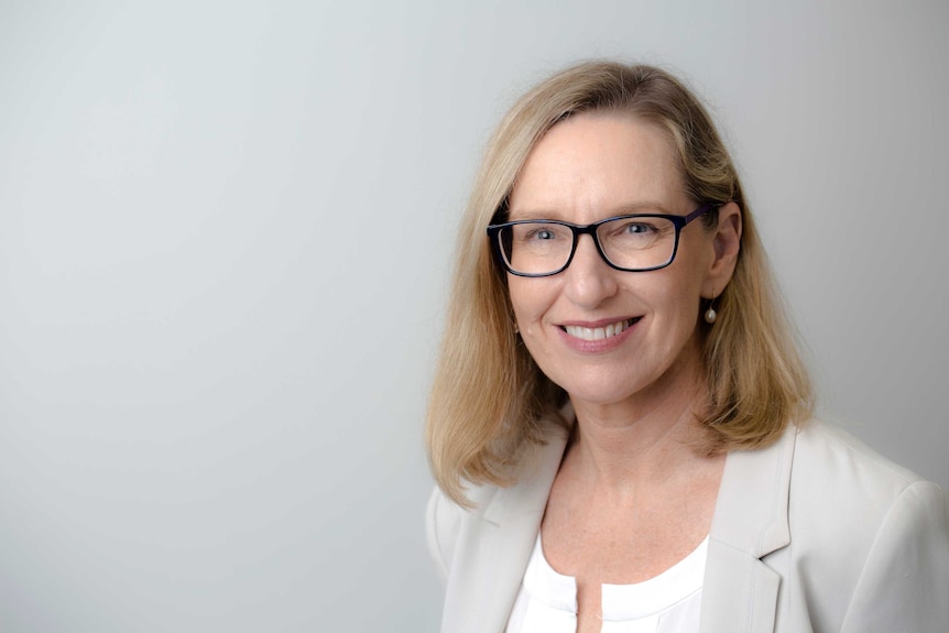 A woman in front of a plain, grey background.