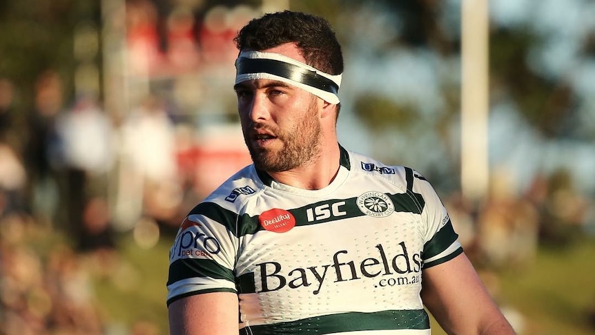 Profile photo of a rugby player in green and white striped jersey and tape around his head.