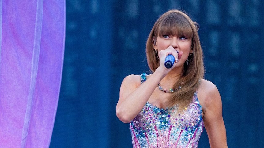 A close up of Taylor Swift on stage, wearing a bejewelled leotard. 