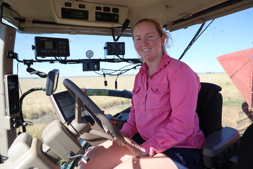 A woman sitting in a tractor cab smiling. 