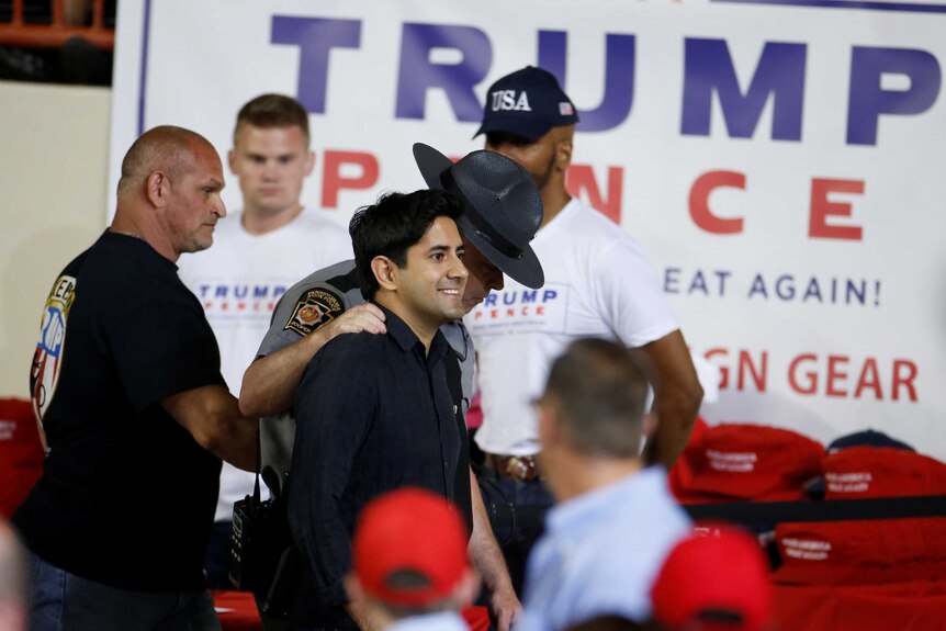 A protester is ejected by a Bikers for Trump member and a law enforcement officer