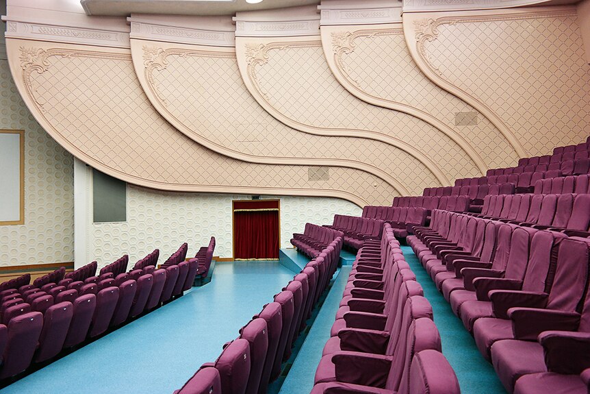 Colour photograph of the side view of the National Drama Theatre in Pyongyang featuring imperial purple coloured seats.