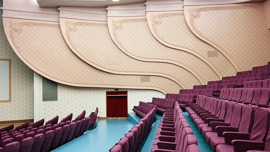 Colour photograph of the side view of the National Drama Theatre in Pyongyang featuring imperial purple coloured seats.