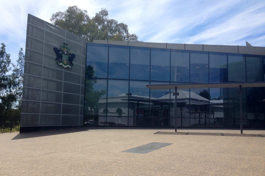 A dark paneled modern building with a glass-window facade 