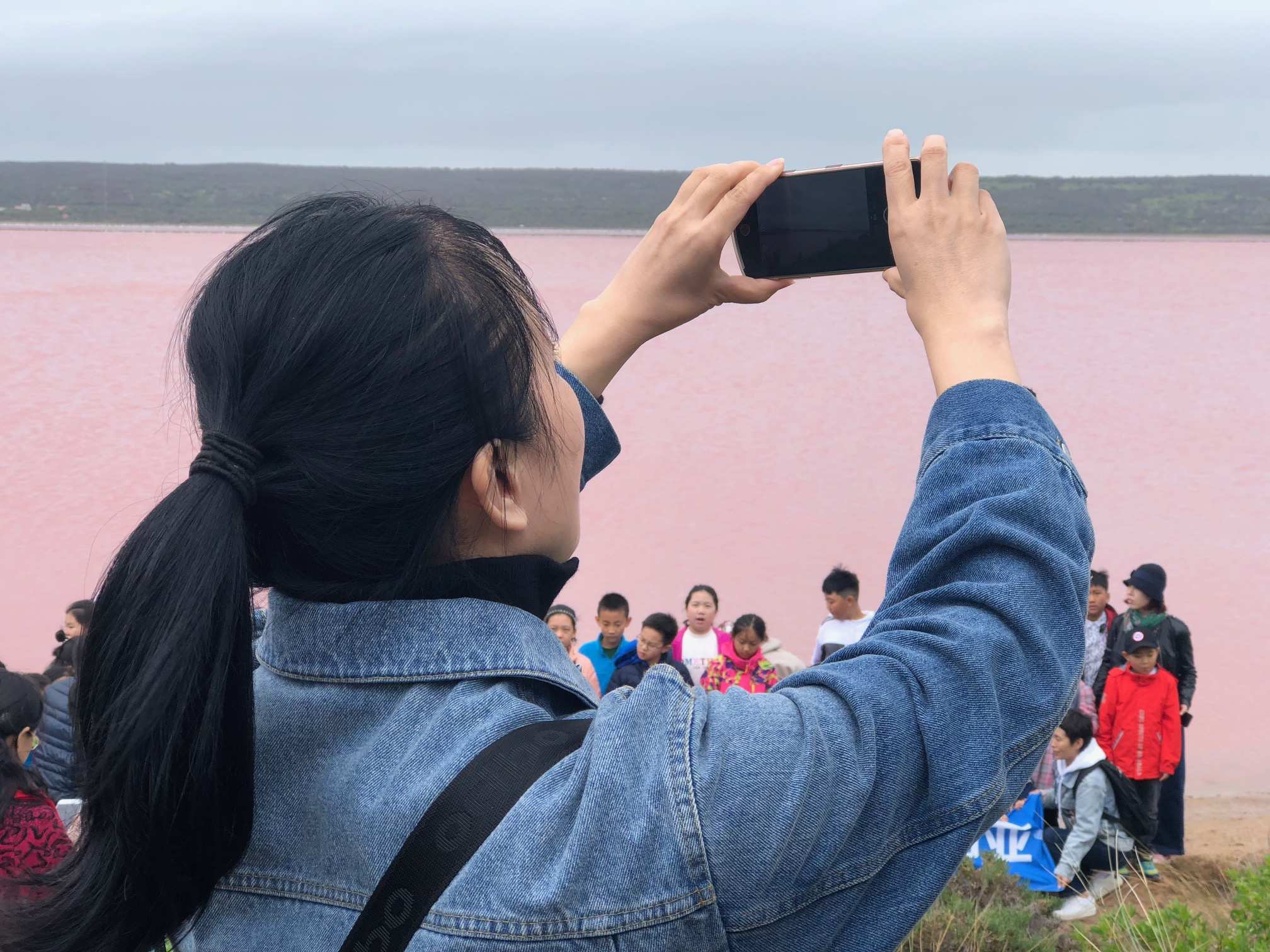 Chinese woman photographs friends at a pink lake in WA's Mid West.
