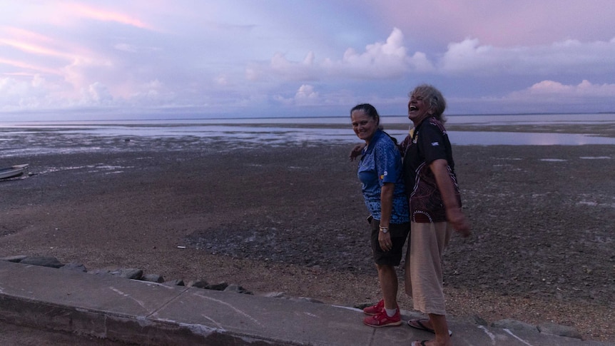 two women on a sea shore, laughing and relaxing