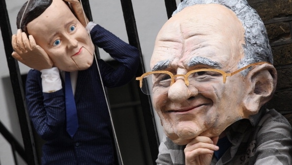 A protester wearing a Rupert Murdoch mask controls a David Cameron puppet. (Getty Images: Oli Scarff)