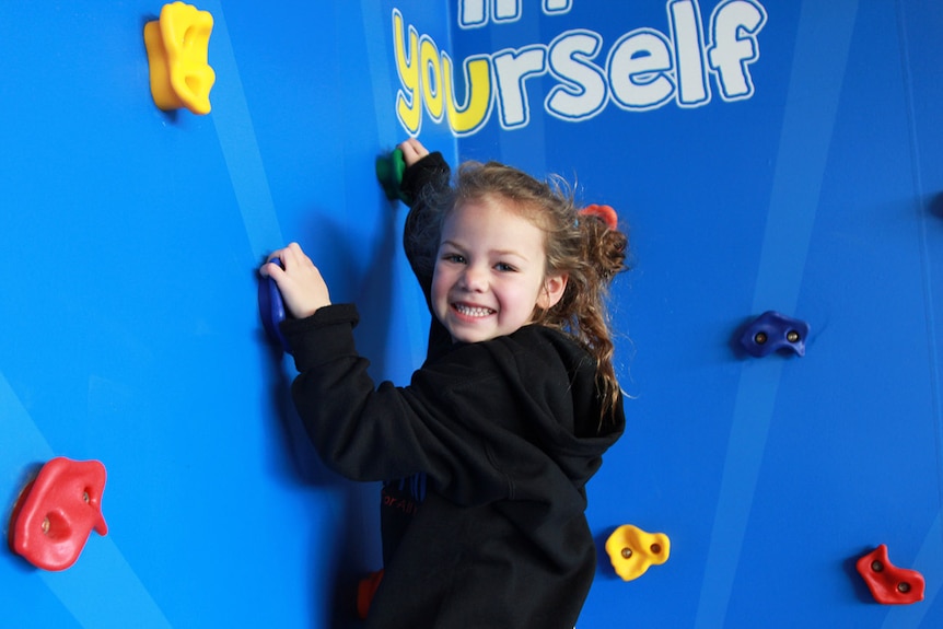 Clementine Johnson, 5, climbs a rock wall.