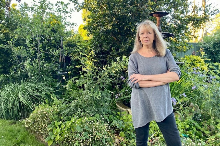 Bev Foster standing in front of a lush green garden.