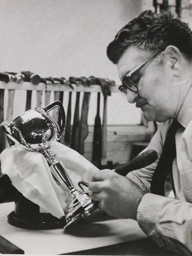 Black and white photo of man working on Cup trophy