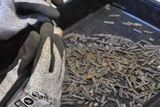 A close up photo of gloved hands handling hundreds of tiny silver lead print types.