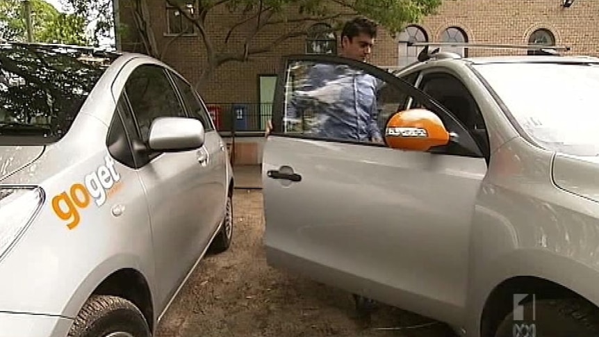 A man getting into a white car.