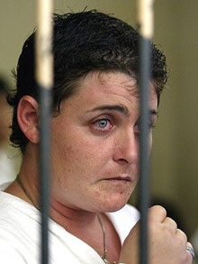 A woman cries behind bars