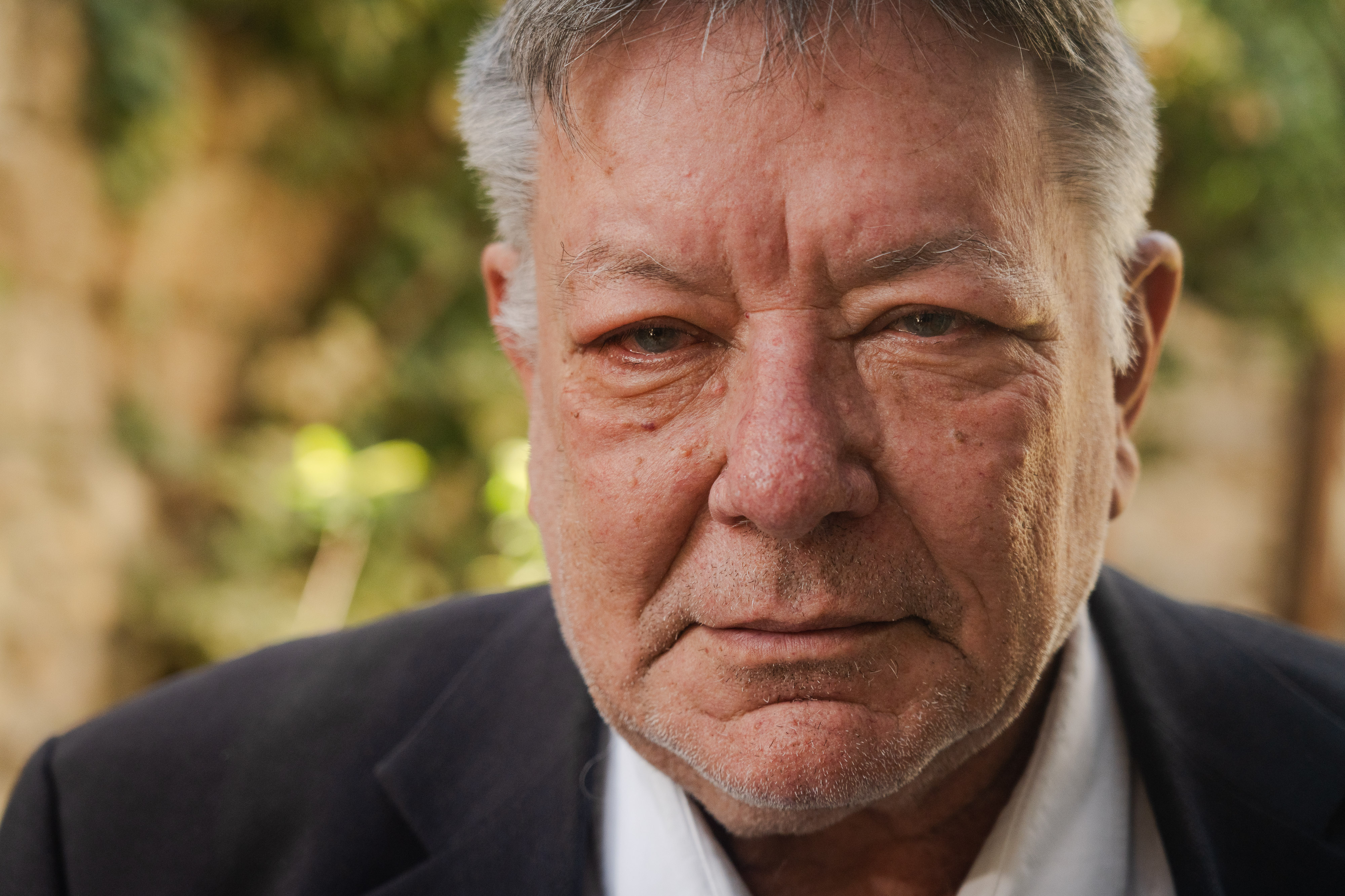 A close up of the face of a man wearing a suit.
