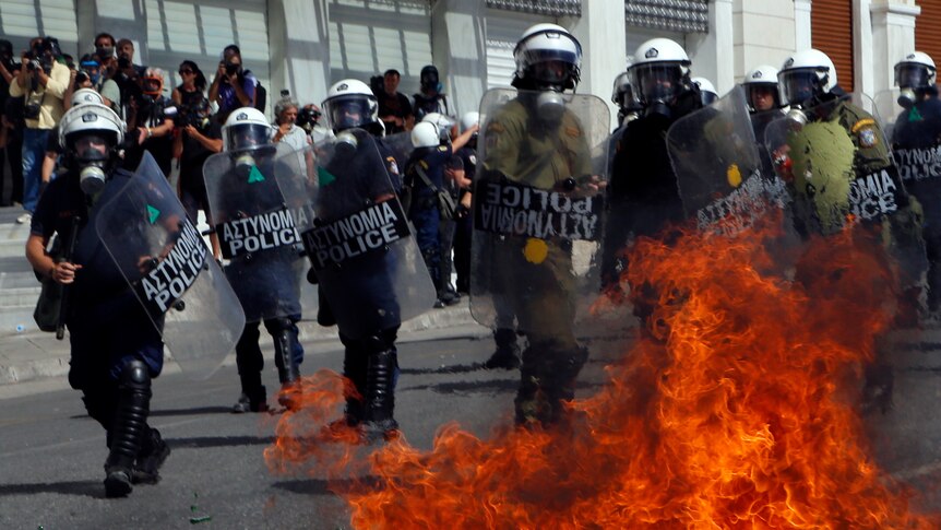A molotov cocktail explodes beside riot police officers near Syntagma square during a 24-hour labour strike in Athens.