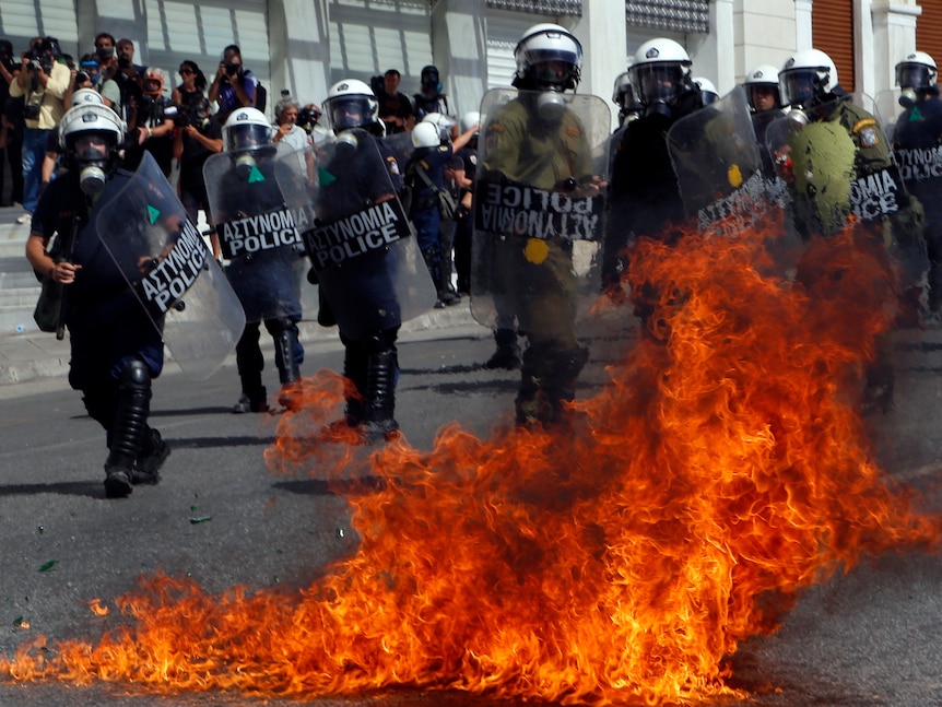A molotov cocktail explodes beside riot police officers near Syntagma square during a 24-hour labour strike in Athens.