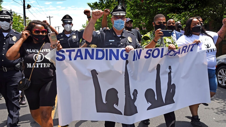 Camden County Metro Police Chief Joe Wysocki raises a fist while marching with Camden residents and activists.