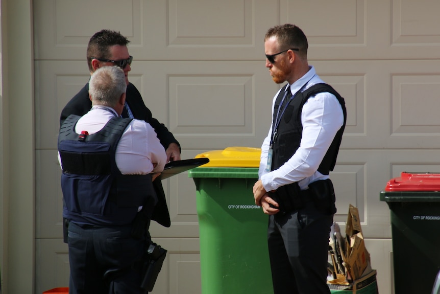 Police stand outside the garage of a suburban home