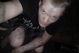 A man with tattoos and short hair, wearing a black t-shirt.