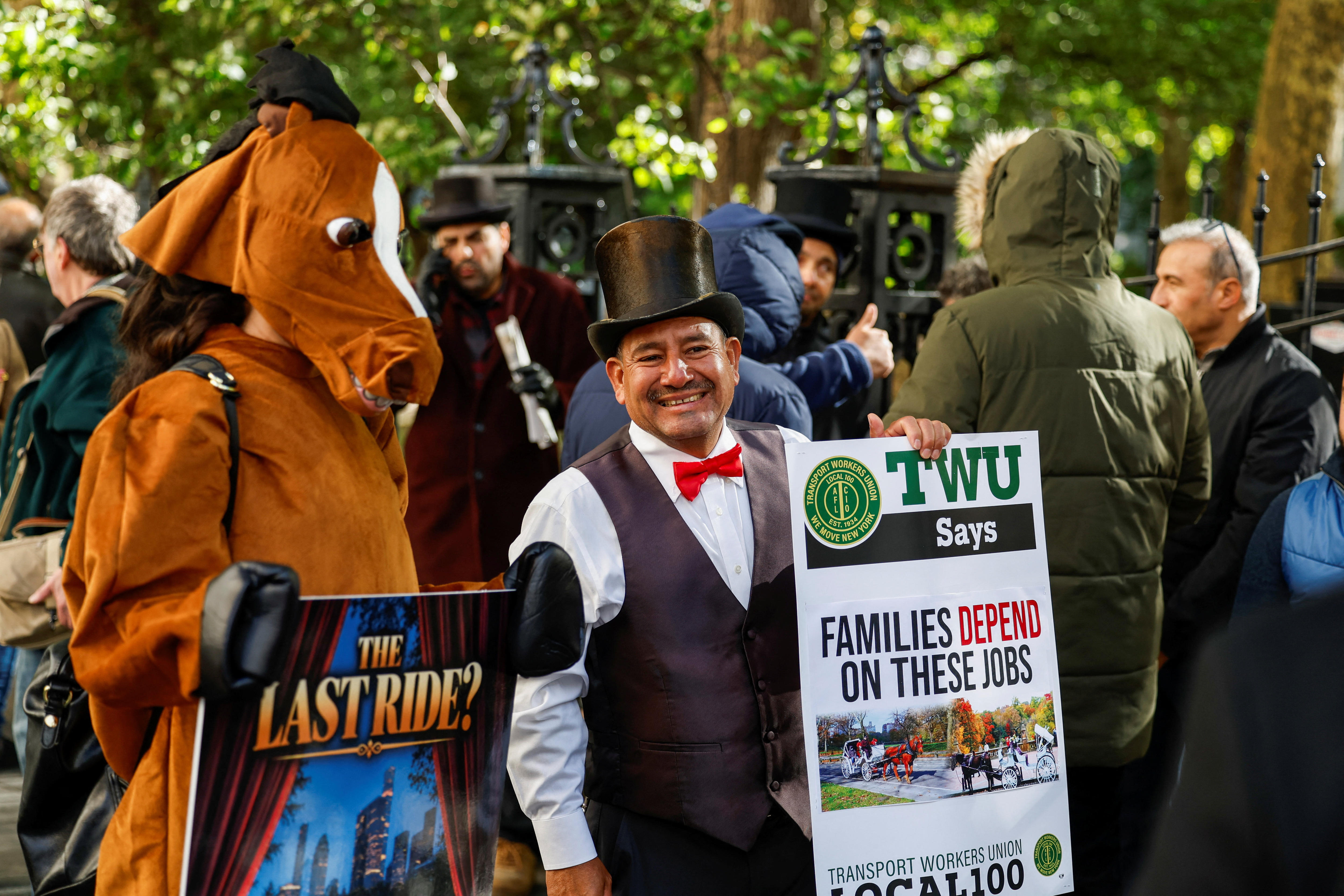 Demonstrators, including one in a horse costume and another in a top hat, stand in Central Park.