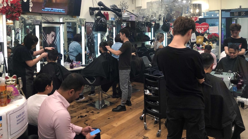 A Melbourne barber shop is packed with patrons.