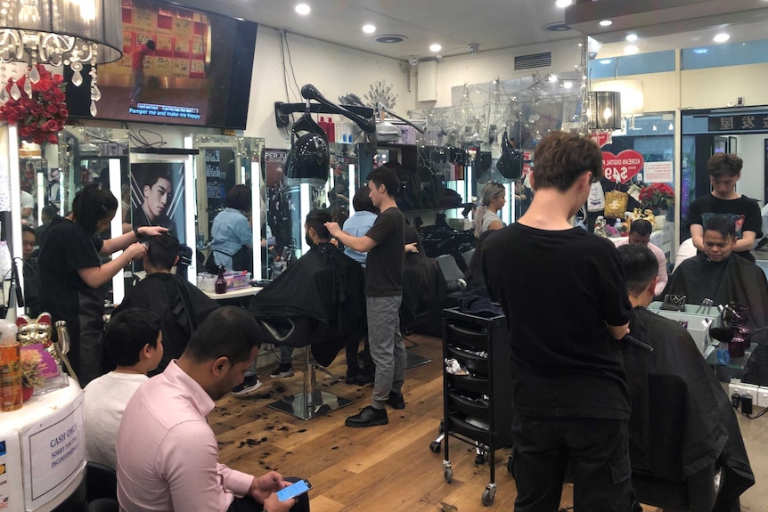 A Melbourne barber shop is packed with patrons.