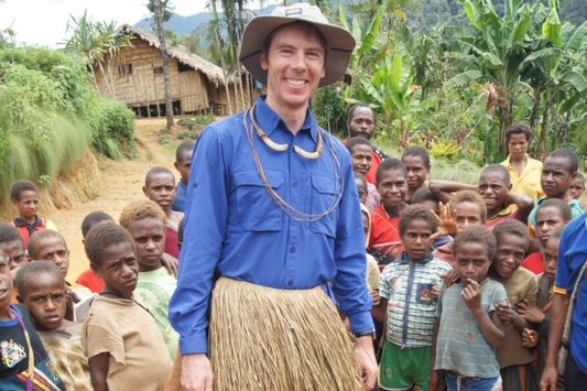 Correspondent Eric Tlozek wears a traditional PNG skirt, surrounded by schoolchildren