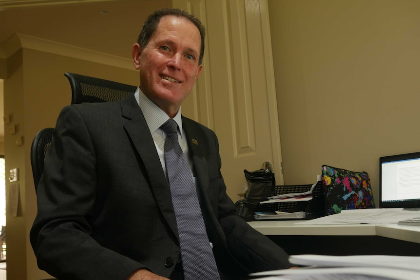 Mark Breckenridge sits at his desk.