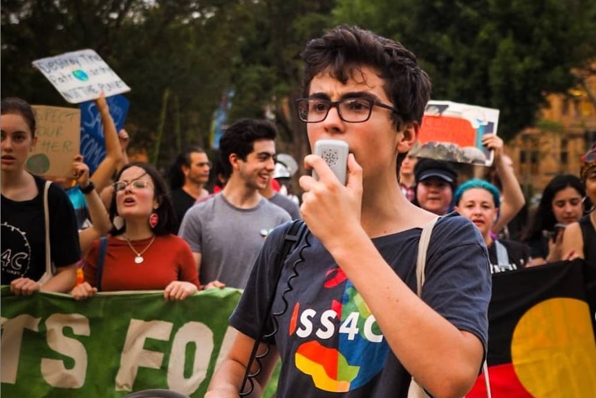 Ambrose Hayes with a laptop computer, it has a sticker for the school climate strike on it.