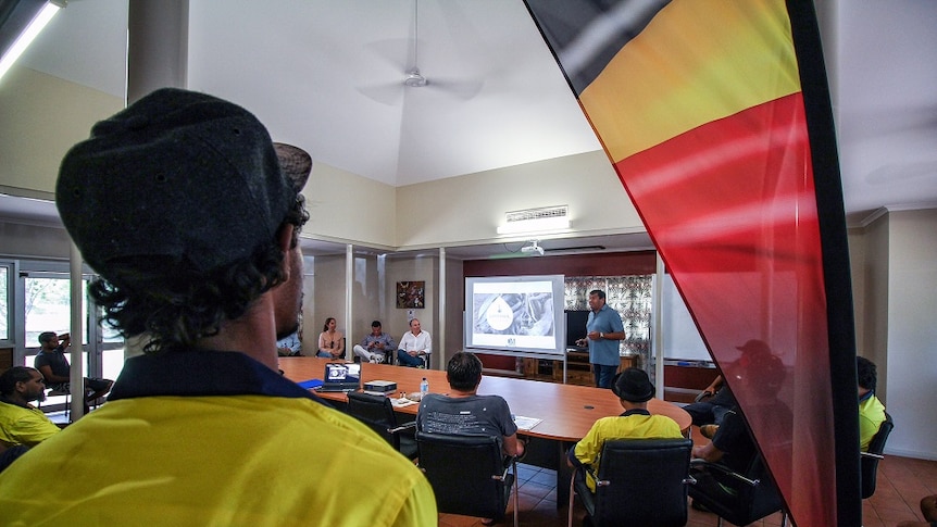 An aboriginal man stands with his back to the camera, watching the recruitment session at the Waringarri Aboriginal Corporation.