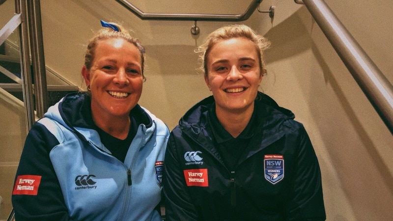 Two women sitting on a stairwell smiling.