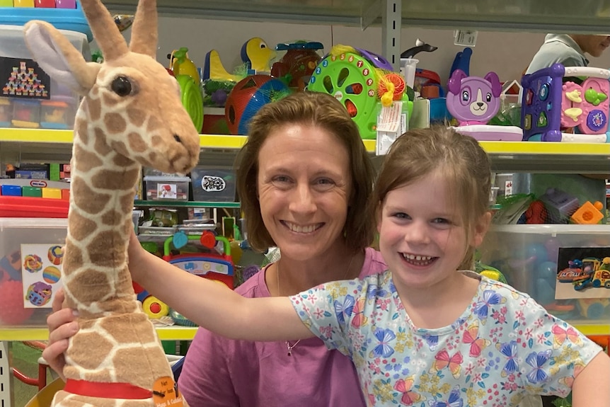 A woman and girl smiling with a toy giraffe 