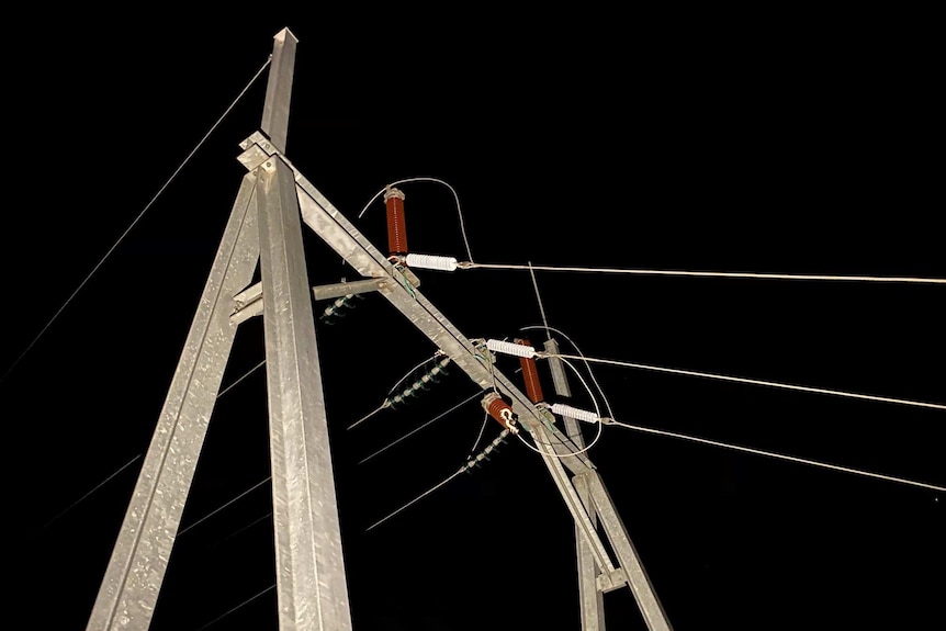 A metal stand with wires stemming out from it, against the night sky.