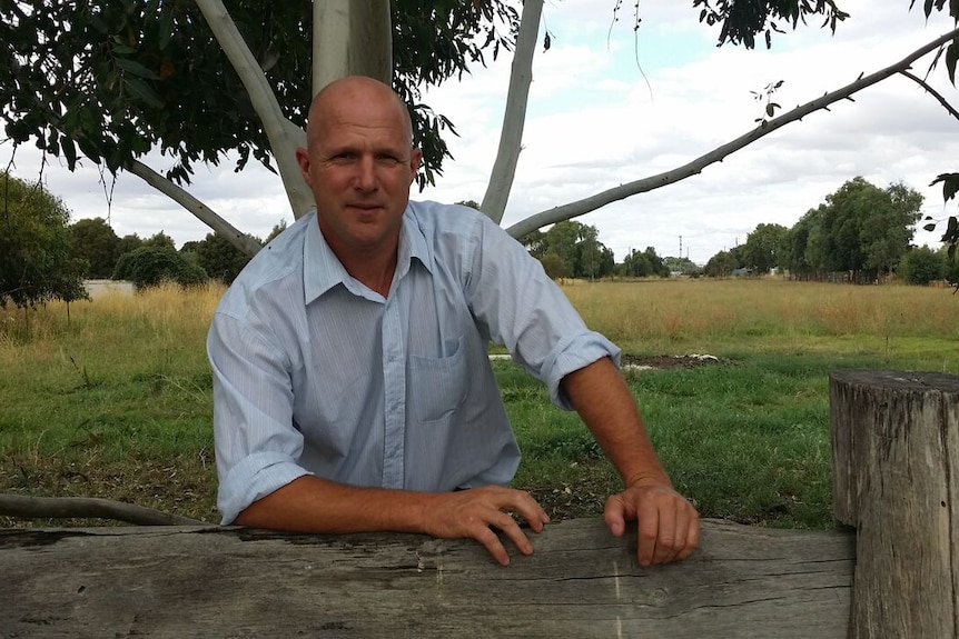 A man leaning on a post-and-rail fence