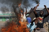 Protesters in Burundi stand behind burning barricade