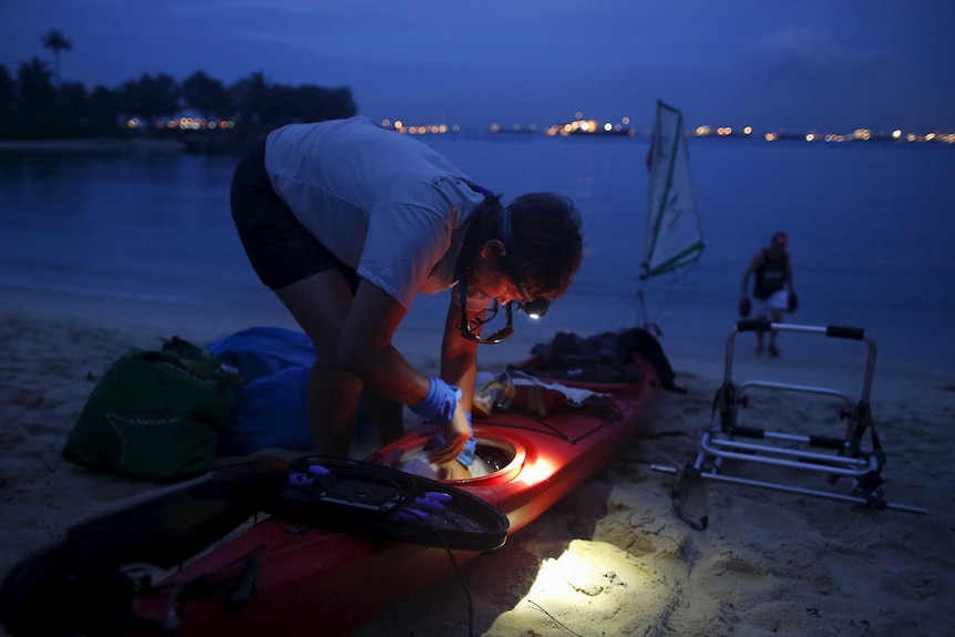 Sandy Robson prepares her kayak by torchlight as she prepares to launch from Tanjong Beach in Singapore.