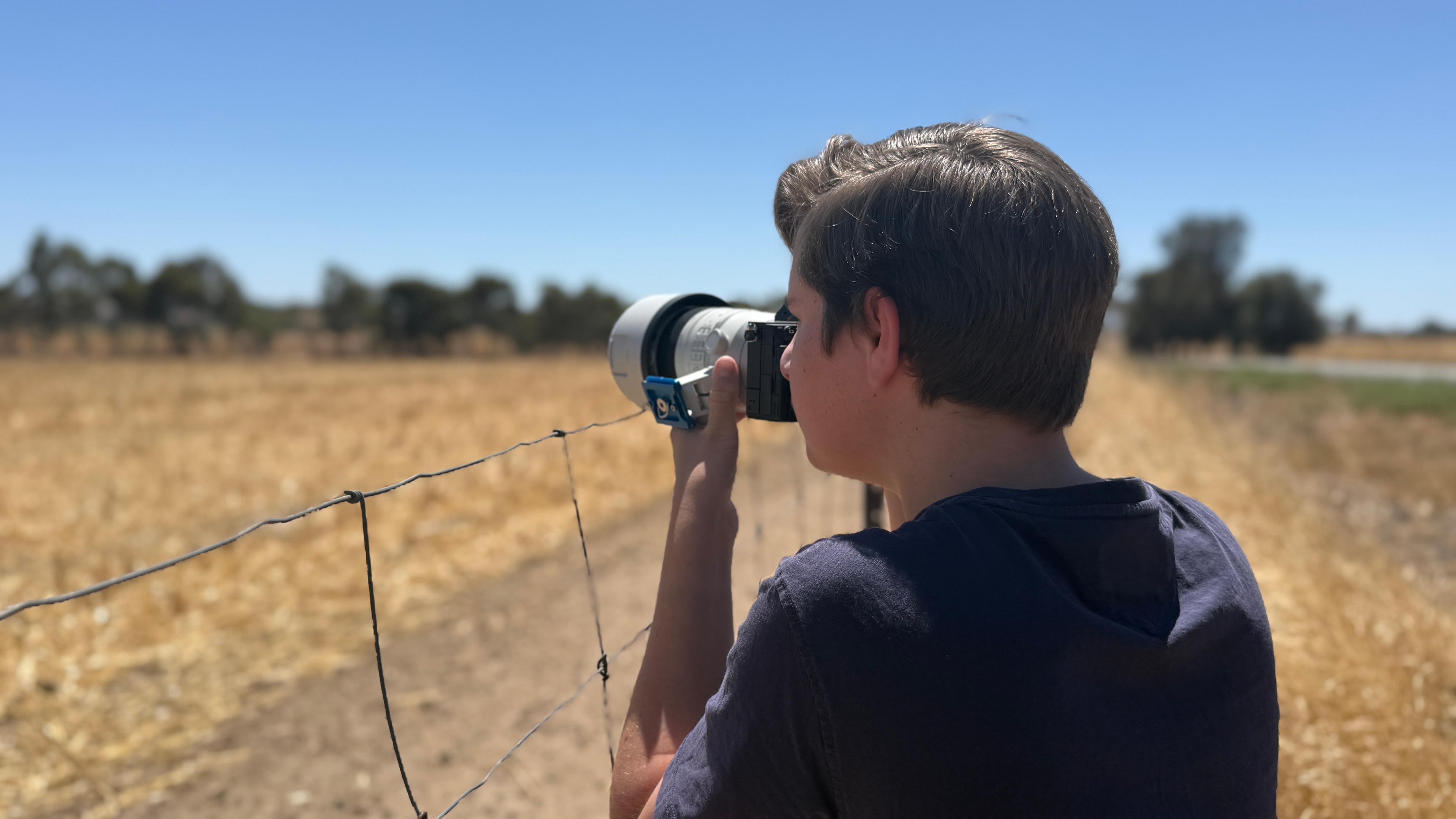 A young man takes a photo on a rural property.