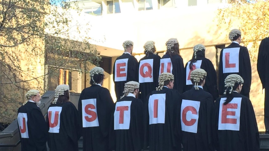 Lawyers line up to spell out "equal justice" on their backs.