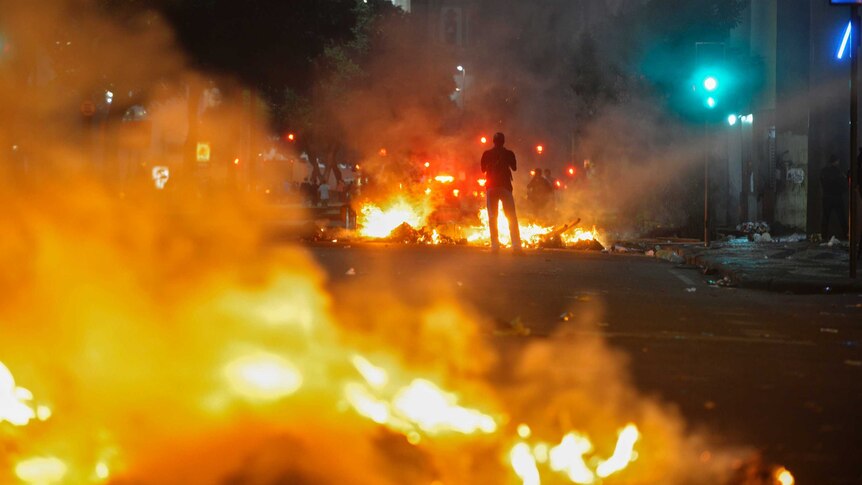 A man stands between bonfires lit by demonstrators as they clashed with police in Rio de Janeiro.