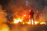 A man stands between bonfires lit by demonstrators as they clashed with police in Rio de Janeiro.